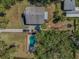 Aerial view showcasing the property with pool, house, long driveway, and mature trees at 6521 Oelsner St, New Port Richey, FL 34652