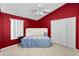 Cozy bedroom features red walls, plush carpet, and a comfortable bed with white tufted headboard and soft bedding at 6521 Oelsner St, New Port Richey, FL 34652