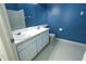 Well-lit bathroom featuring a dual sink vanity, toilet, and blue accent wall at 8545 Hunters Key Cir, Tampa, FL 33647