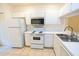A white kitchen featuring bright tiled flooring, modern stainless steel appliances, and white cabinetry at 8545 Hunters Key Cir, Tampa, FL 33647