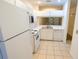 Clean, galley kitchen featuring white appliances and cabinets, plus tiled flooring and lots of natural light at 8545 Hunters Key Cir, Tampa, FL 33647