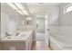 Bright bathroom featuring double sinks, tile flooring, large mirrors, a bathtub and a separate shower at 9329 Huntington Park Way, Tampa, FL 33647