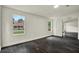 Bedroom with dark wood-look floors, white walls, large windows, and an open doorway to a hall at 9690 Jerome Dr, New Port Richey, FL 34654