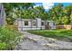 Exterior view of home with a gravel driveway, green lawn, and partially wooded area offering privacy at 9690 Jerome Dr, New Port Richey, FL 34654