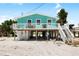 Charming raised beach house with a white porch and a staircase at 9760 Little Gasparilla Island, Placida, FL 33946