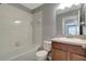 Bathroom with combination tub and shower, wood-look vanity, and white tile at 1107 Seminole Sky Dr, Ruskin, FL 33570