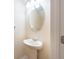 Elegant pedestal sink with oval mirror and updated lighting in a half bathroom at 11903 Greengate Dr, Hudson, FL 34669