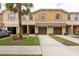 Townhome exterior featuring garages, front lawns, and partial palm tree at 11903 Greengate Dr, Hudson, FL 34669