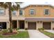 Exterior shot of townhomes featuring attached garages and manicured landscaping at 11903 Greengate Dr, Hudson, FL 34669