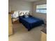 Cozy bedroom with patterned carpet, window, wooden bedside table, and blue quilt on the bed at 1200 37Th N St # 403, St Petersburg, FL 33713