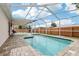 Refreshing screened-in pool area with a brick paver patio, lounge chairs, and privacy fence at 12279 Elmore Dr, Spring Hill, FL 34609