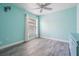 A light-blue bedroom has wood floors, a window, and a ceiling fan at 12813 Kings Lake Dr, Gibsonton, FL 33534