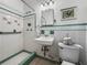 Bathroom featuring green and white tilework, pedestal sink, and walk-in shower at 1445 Wilson Rd, Clearwater, FL 33755