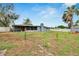 This expansive backyard includes a screened-in porch, mature trees, a fire pit, and varied fencing for privacy at 1607 Melodie Dr, Brandon, FL 33510