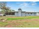 The backyard features a screened-in porch, lush lawn, mature trees, and a fire pit for outdoor relaxation and entertainment at 1607 Melodie Dr, Brandon, FL 33510