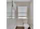The bright bathroom showcases a glass shower door, wood-look tile floors, and a toilet with a window at 1607 Melodie Dr, Brandon, FL 33510