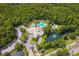 Aerial view shows community with multiple pools, clubhouse, and a tranquil lake with fountain amidst lush greenery at 16206 Nottingham Park Way, Tampa, FL 33647