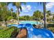 Resort-style community pool with waterslide, seating, and lush palm trees offers an ideal space for recreation and relaxation at 16206 Nottingham Park Way, Tampa, FL 33647