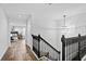 Upstairs hallway with dark wood floors, black railings, a modern chandelier, and view into a bedroom at 16206 Nottingham Park Way, Tampa, FL 33647