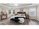 Bright main bedroom featuring a tray ceiling, hardwood floors, and a large bed with accent pillows at 16206 Nottingham Park Way, Tampa, FL 33647