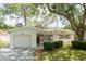 Charming single-story home featuring a one-car garage, red shutters, and lush green landscaping at 2222 Euclid N Cir, Clearwater, FL 33764