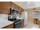 Bright kitchen with wood cabinets, a stainless steel microwave, and a view into the dining room at 2222 Euclid N Cir, Clearwater, FL 33764