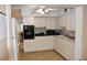 A compact kitchen featuring white cabinets, black appliances, and durable tile flooring at 2463 Brazilia Dr # 43, Clearwater, FL 33763