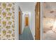 Long hallway features unique wallpaper, blue carpeting, and several doorways in the home at 2724 W Henry Ave, Tampa, FL 33614