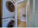 Modern laundry area featuring stacked washer and dryer near an open door to the bathroom at 2749 Countryside Blvd # 4, Clearwater, FL 33761