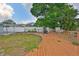 View of the backyard with a wooden deck, partial fencing, and mature trees that provide shade and privacy at 3411 W Beach St, Tampa, FL 33607