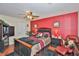 Cozy bedroom featuring a ceiling fan and an inviting red accent wall with dark wood accents at 3411 W Beach St, Tampa, FL 33607