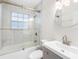 Bright bathroom featuring a tub with shower, glass door, white marble tiles, and modern vanity sink at 366 12Th Ave, Indian Rocks Beach, FL 33785