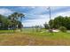Scenic view of the community's grassy lawn near the water with palm trees and a flag pole under a beautiful blue sky at 3716 Janus Way, Palm Harbor, FL 34685