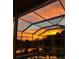 Scenic backyard view of the pool and spa with a vibrant sunset at 3716 Janus Way, Palm Harbor, FL 34685
