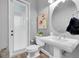 Cozy powder room features a pedestal sink, round mirror, toilet, and door leading to the outside at 3716 Janus Way, Palm Harbor, FL 34685