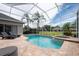 A screened-in pool and spa are surrounded by brick pavers, with seating and a beautiful backyard view at 3716 Janus Way, Palm Harbor, FL 34685