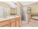Bathroom featuring a double vanity, framed mirror, glass-enclosed shower, and soaking tub at 4528 Amberly Oaks Ct, Tampa, FL 33614