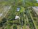 Aerial view of the property featuring a house, pond, mature trees, and expansive green space at 4858 Troydale Rd, Tampa, FL 33615