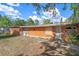 Back exterior view of the house, featuring boarded windows and doors, with a yard area and some landscaping at 4858 Troydale Rd, Tampa, FL 33615