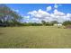 Expansive grassy area surrounded by lush vegetation with a trailer and wood pile on the property at 4858 Troydale Rd, Tampa, FL 33615
