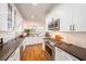 Bright kitchen with white cabinets, modern appliances, black countertops, and a view to the dining and living area at 5015 S Elberon St, Tampa, FL 33611