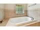 Relax in this soaking tub with tile surround, featuring a glass block window for added privacy at 5702 Ainsworth W Ct, Tampa, FL 33647