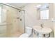 Well-lit bathroom featuring a tiled shower with glass door, pedestal sink, and modern fixtures at 5702 Ainsworth W Ct, Tampa, FL 33647
