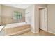 Relaxing bathroom featuring a large soaking tub, decorative tile work, and a privacy window at 5702 Ainsworth W Ct, Tampa, FL 33647