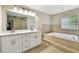 This primary bathroom features a double vanity, soaking tub and neutral tile at 5702 Ainsworth W Ct, Tampa, FL 33647