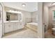 Well-lit bathroom featuring a soaking tub, double vanity, and tiled floor at 5702 Ainsworth W Ct, Tampa, FL 33647