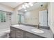 Bathroom with a granite countertop, dual sinks, and a shower with glass block window, offering modern features at 5702 Ainsworth W Ct, Tampa, FL 33647