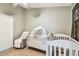Bright bedroom featuring a white crib, ceiling fan, and natural light from a window at 5702 Ainsworth W Ct, Tampa, FL 33647