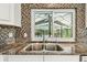 Close up view of gourmet kitchen sink, counter top, backsplash and view to screened in pool at 5702 Ainsworth W Ct, Tampa, FL 33647
