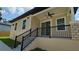 Tan house featuring stairs leading up to the front porch with a black ceiling fan at 7013 N 15Th St, Tampa, FL 33610